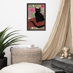 Framed artwork of a black cat on a floral background in a room with a plant, ottoman, and monkey plush toy.